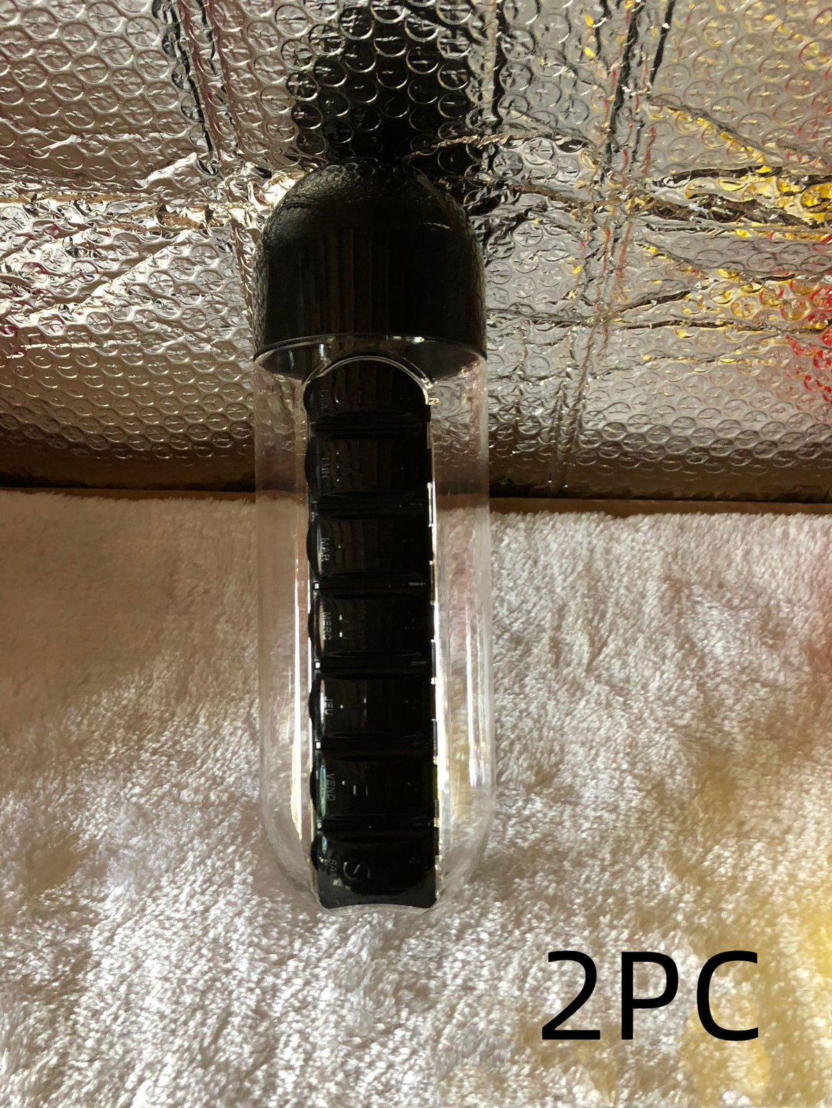 Black DailyDose pillbox water bottle 2-pack, real customer photo on a textured blanket