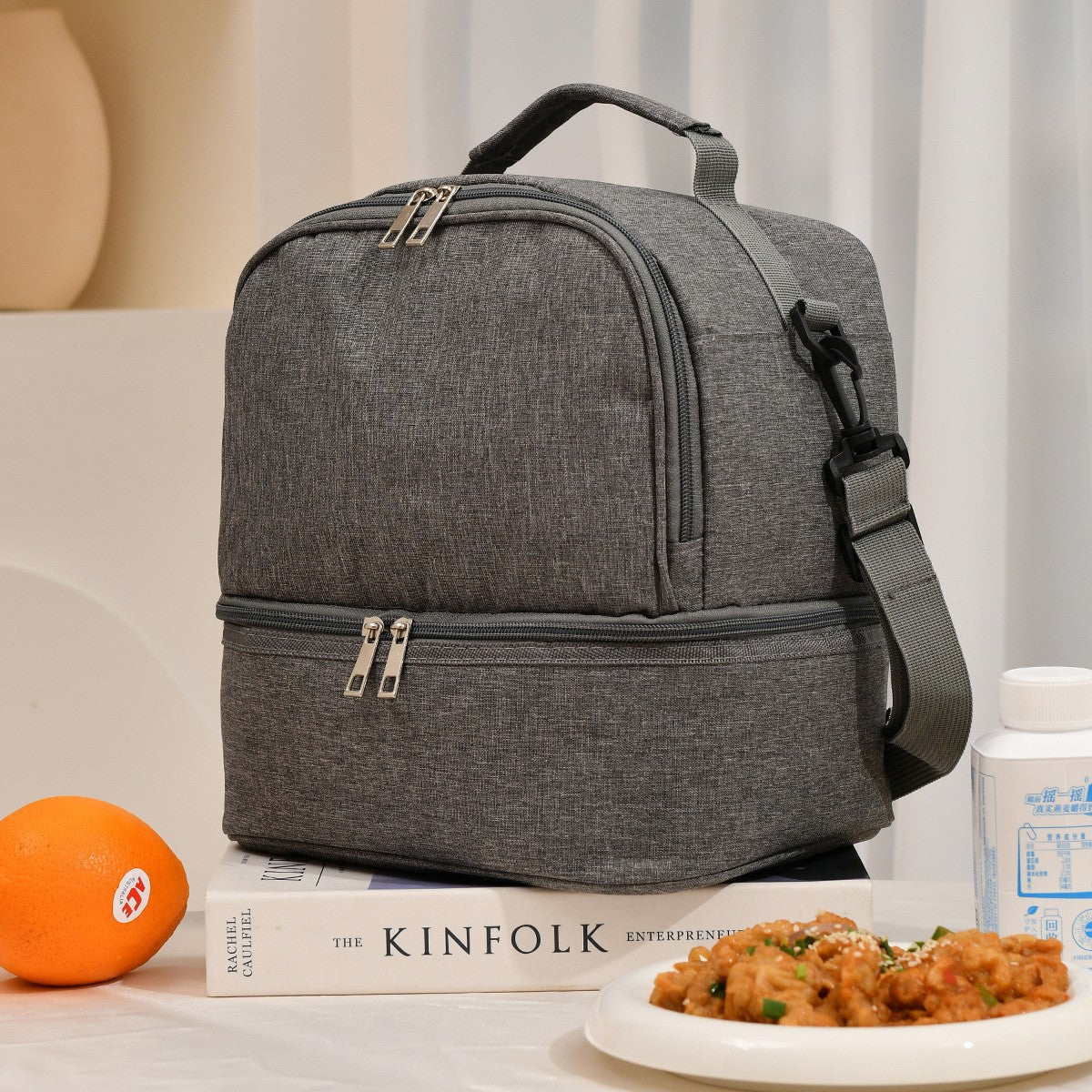 Gray ChillPack insulated lunch bag with food and orange on table