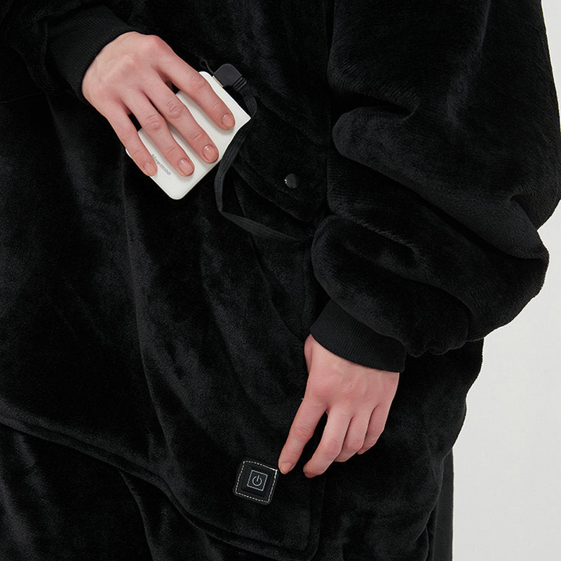 Close-up of hand holding CozyGlow heated hoodie blanket's USB power bank with power button control panel