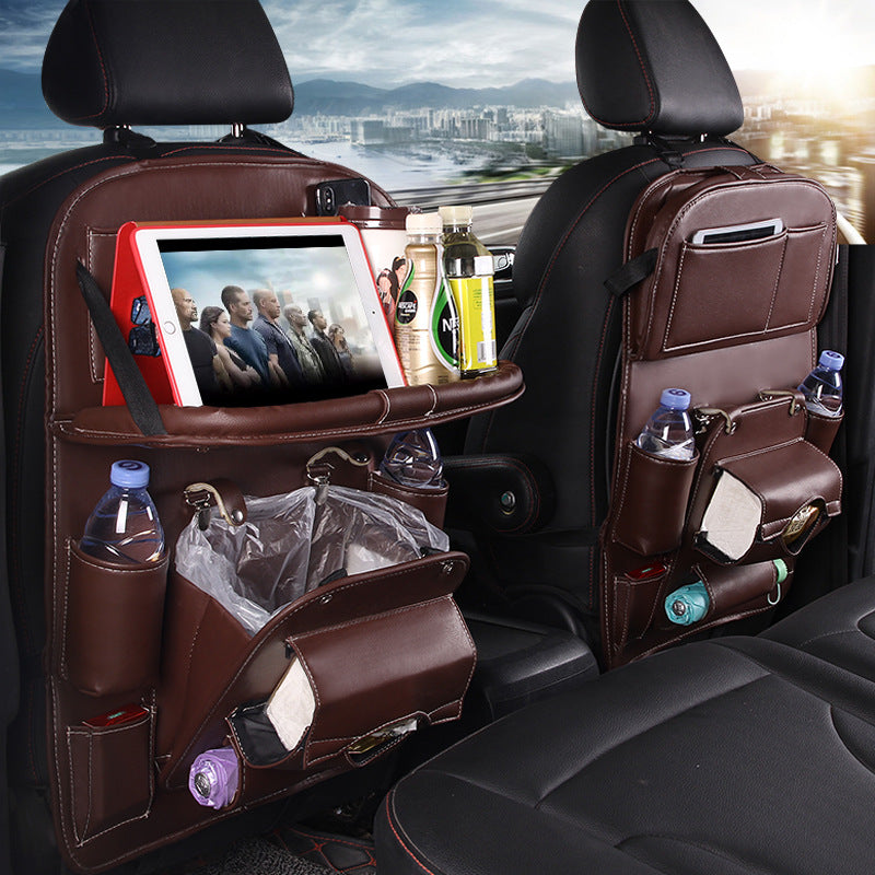 Brown leather RoadTrip car backseat organizer with tablet holder, water bottle pockets, and built-in trash bag, mounted on car seat