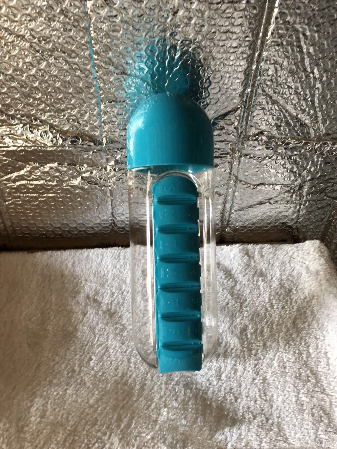Teal DailyDose pillbox water bottle in real-life customer photo on a fabric surface
