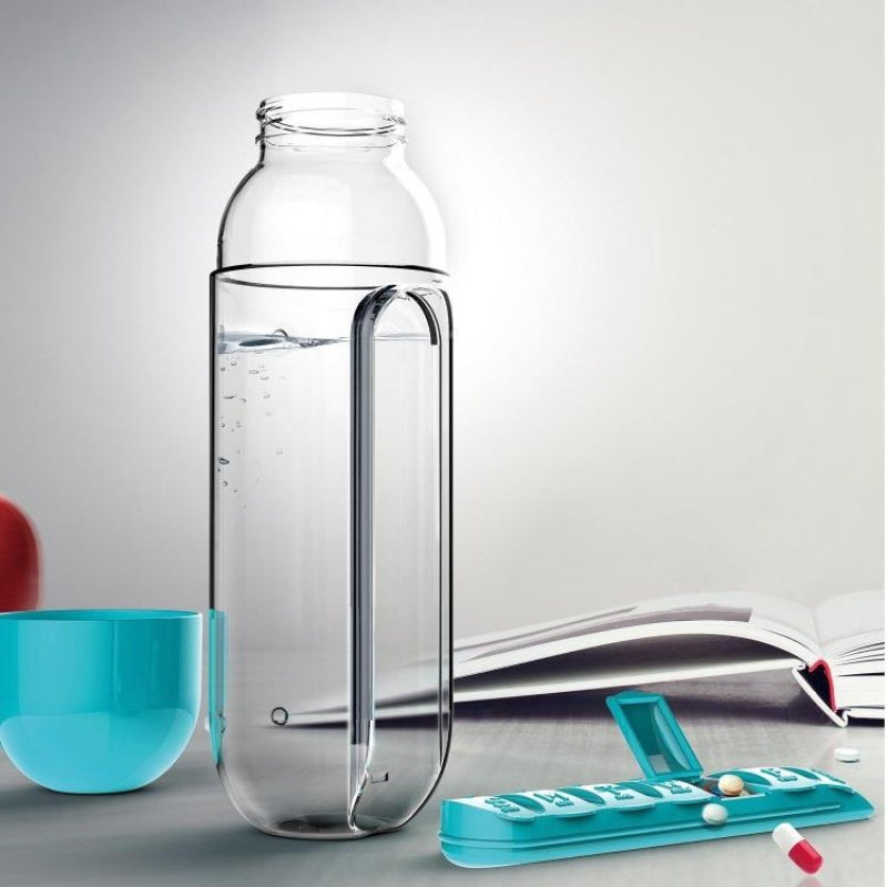 Clear water bottle with detachable teal pill organizer, disassembled next to an open notebook