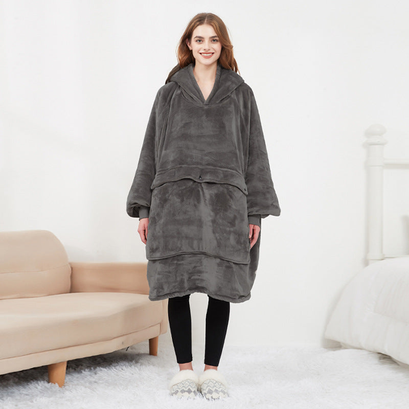 Woman wearing dark gray CozyGlow wearable heated hoodie blanket full-length in white bedroom