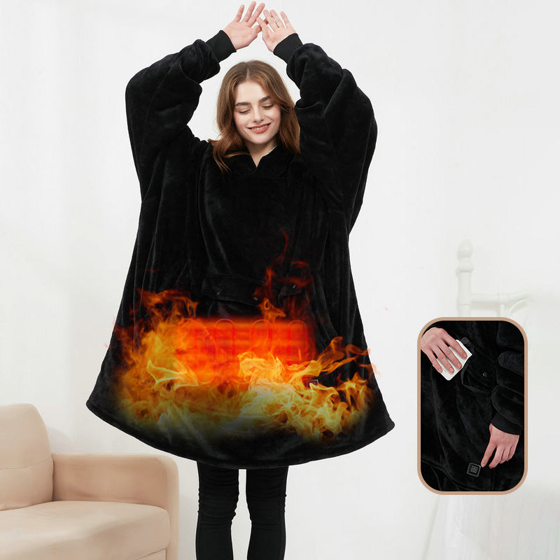 Woman wearing black CozyGlow wearable heated hoodie blanket with flame print heating panel showing USB power bank control