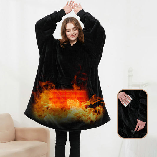 Woman wearing black CozyGlow wearable heated hoodie blanket with flame print heating panel showing USB power bank control