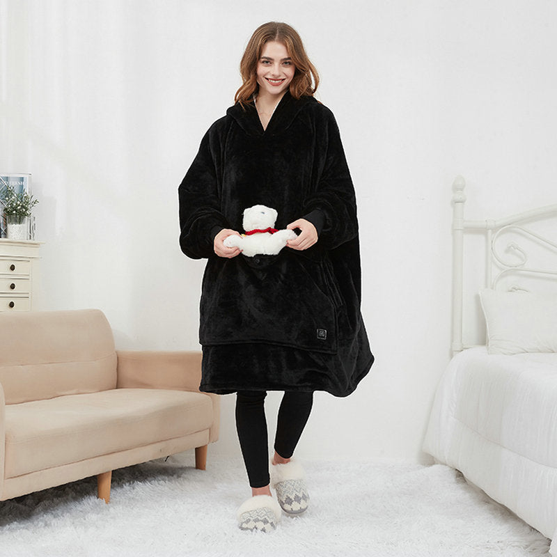 Woman playfully posing in black CozyGlow wearable heated hoodie blanket in a bright bedroom
