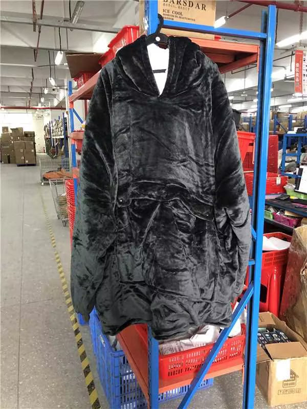 Black CozyGlow heated hoodie blanket hanging on rack showing plush velvet texture and relaxed fit