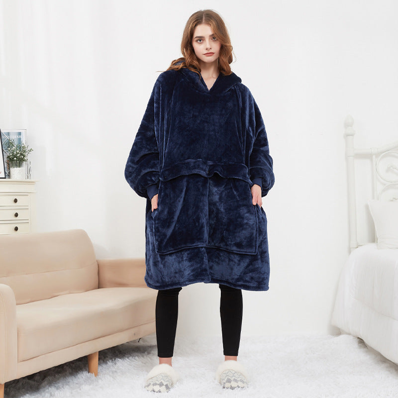 Woman wearing navy blue CozyGlow wearable heated hoodie blanket full-length in white bedroom
