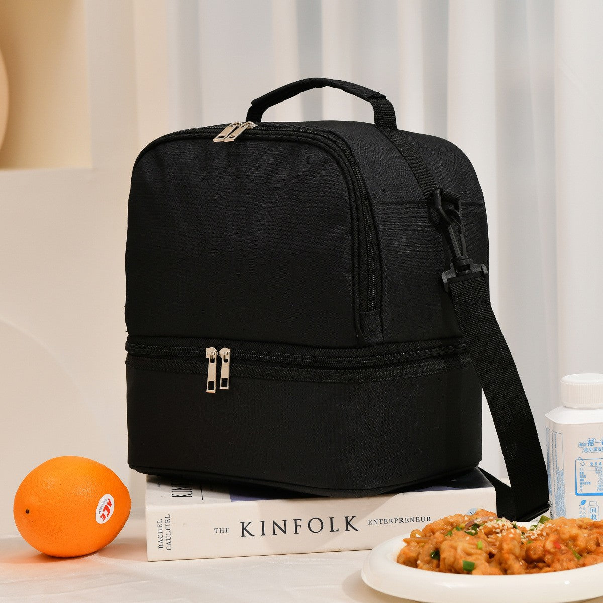 Black ChillPack insulated lunch bag with food and orange on table