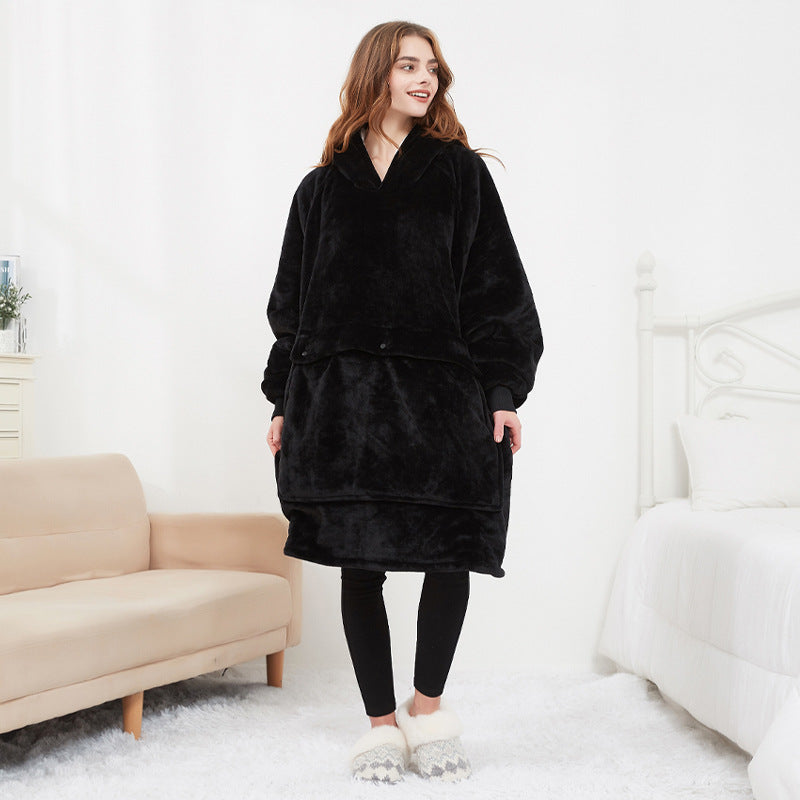 Woman wearing black CozyGlow wearable heated hoodie blanket full-length in white bedroom setting